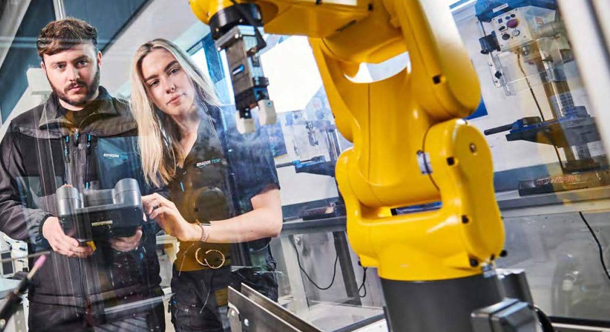 Two engineers using a robot in manufacturing